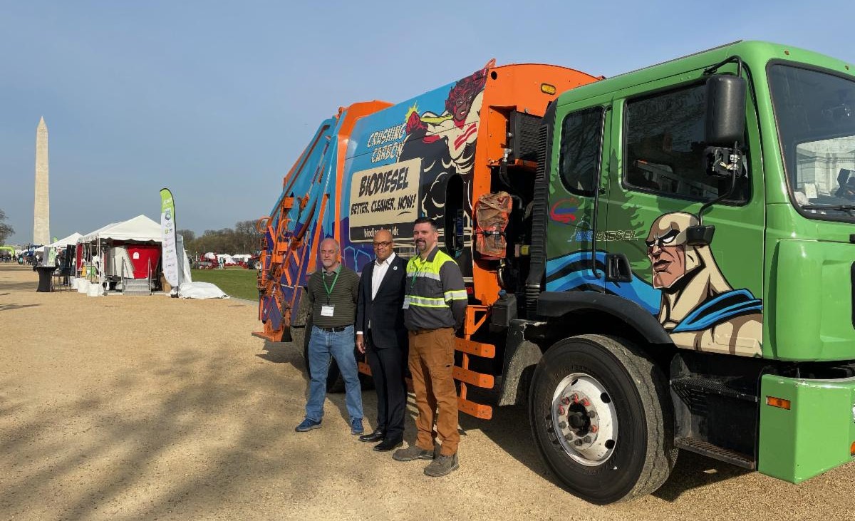 Greater Washington Region Clean Cities and Communities CEO and Executive Director Antoine Thompson (center) stands with two other people in front of a biodiesel waste hauler in the National Mall in Washington, D.C.